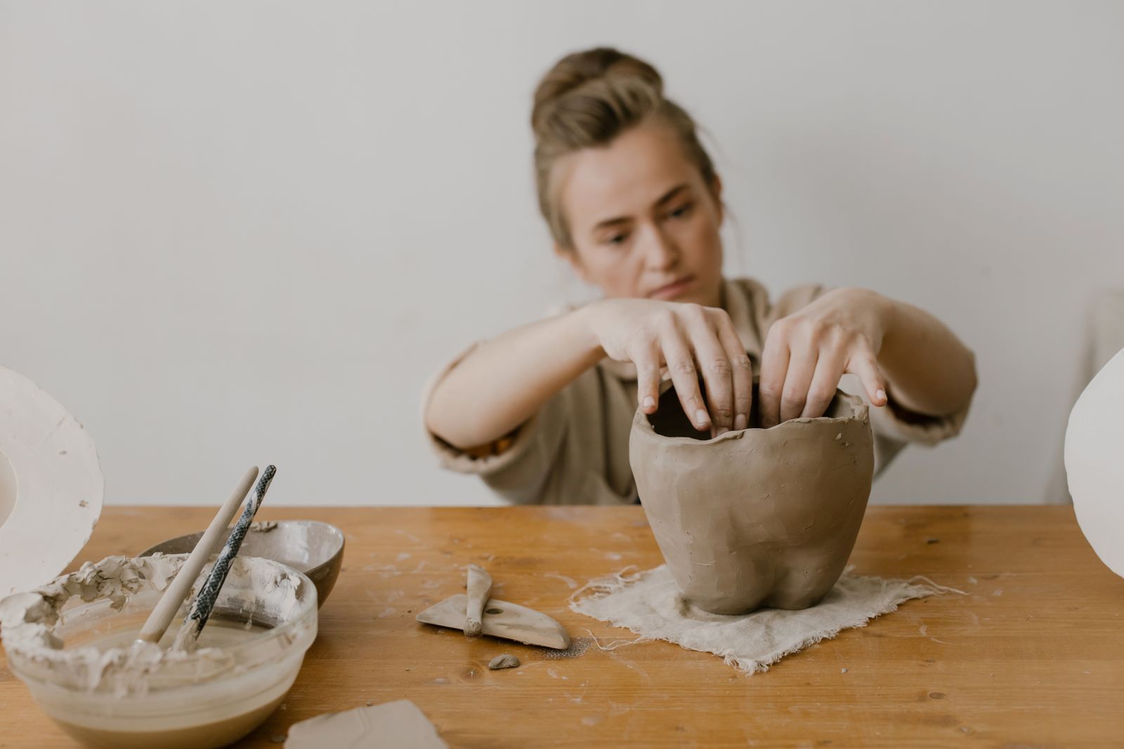 A maker shaping clay in a studio