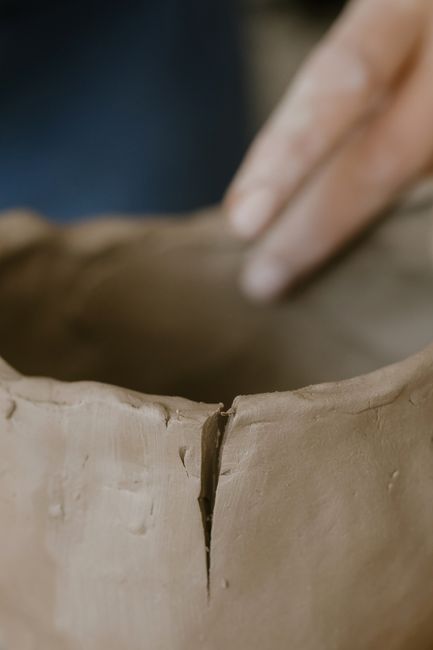 Fotomural Vista detallada de una mano dando forma a la arcilla húmeda, mostrando el proceso de elaboración de cerámica.