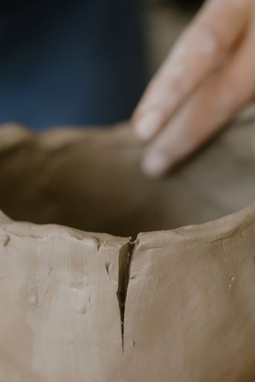 Hand shaping wet clay in a detailed close up