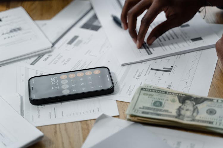 Smartphone Calculator And Dollar Bills On Papers On Table Top