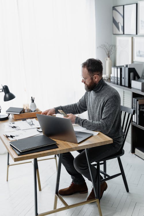 A Man Sitting at a Table With a Laptop