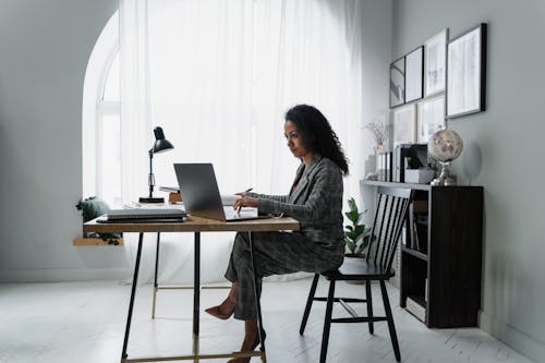 Free Woman in Gray Jacket Sitting on Chair Using Laptop Computer Stock Photo
