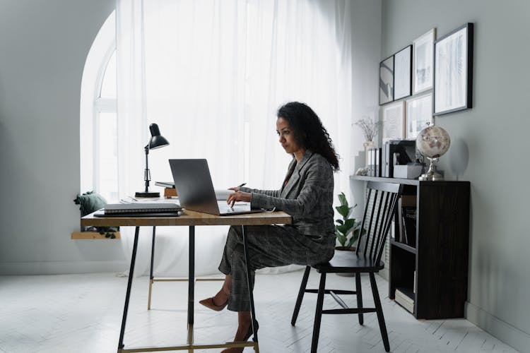 Woman In Gray Jacket Sitting On Chair Using Laptop Computer
