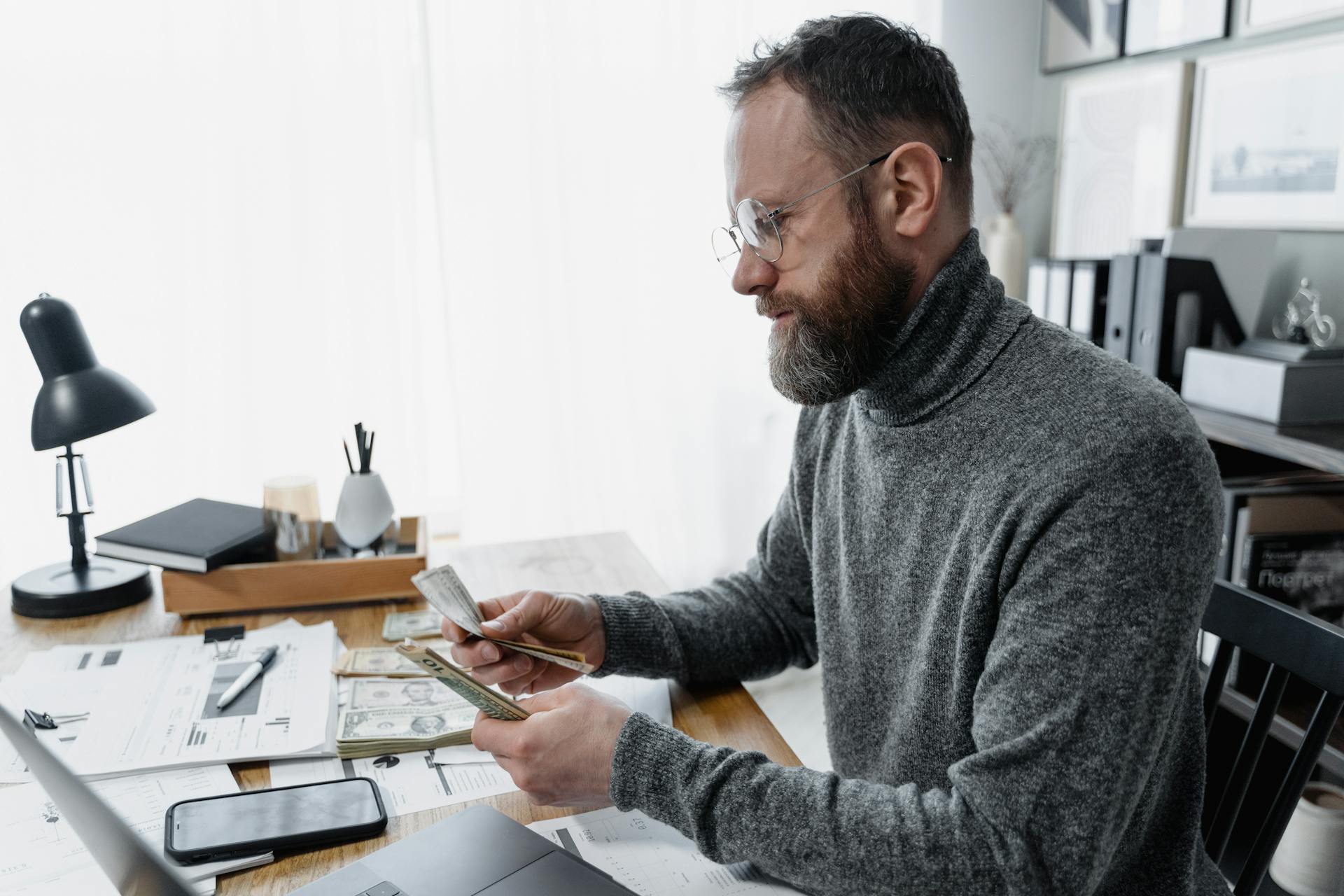 Bearded Man Counting Piles of Dollar Bills