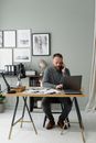 Man Sitting on a Chair in Front of Computer Laptop Using Cellphone