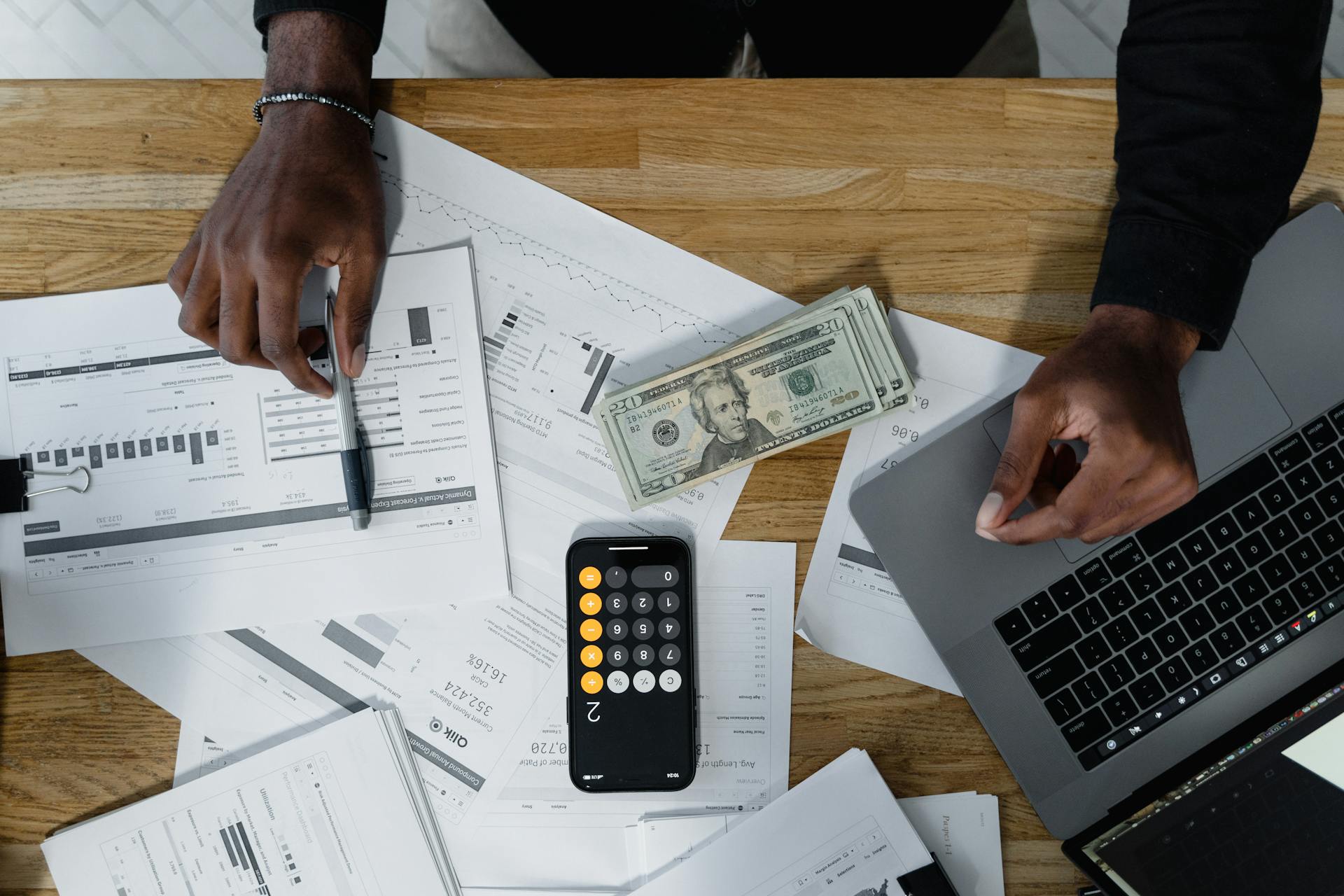 Cash, Computer Laptop, Pen and Paperwork on Wooden Surface