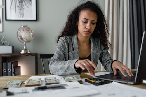 Free A Woman in Plaid Blazer Using Her Laptop and Mobile Phone Stock Photo