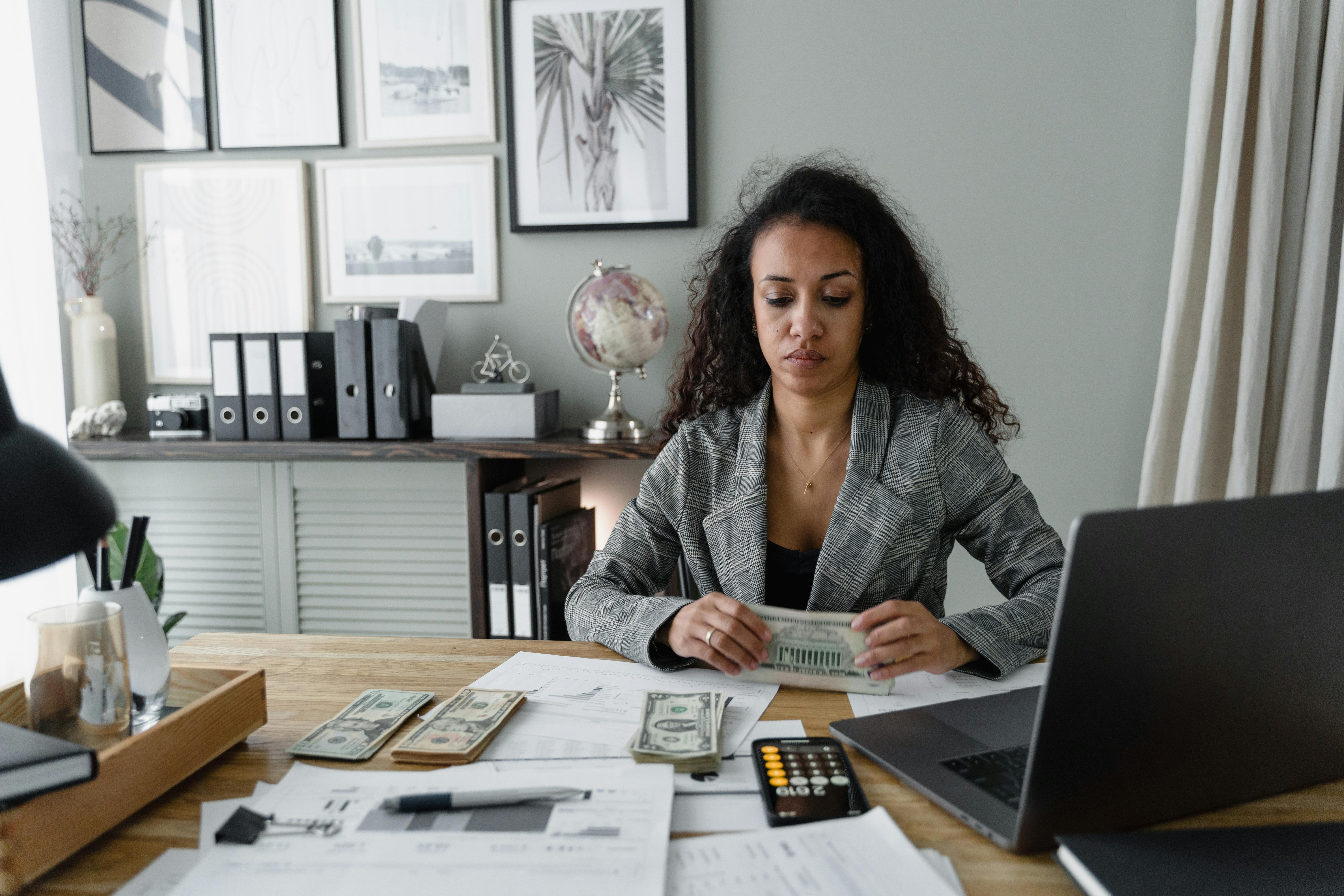 woman holding cash money sitting at a table