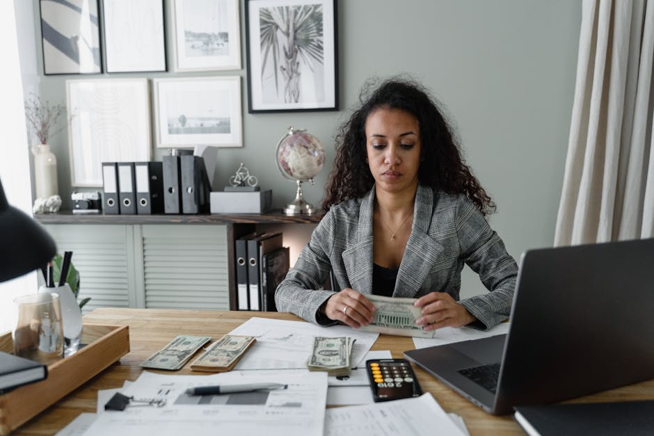 Does Wealthfront Actually Help With Idle Cash Growth? Focused woman counts cash at desk surrounded by office items, emphasizing finance and professionalism.