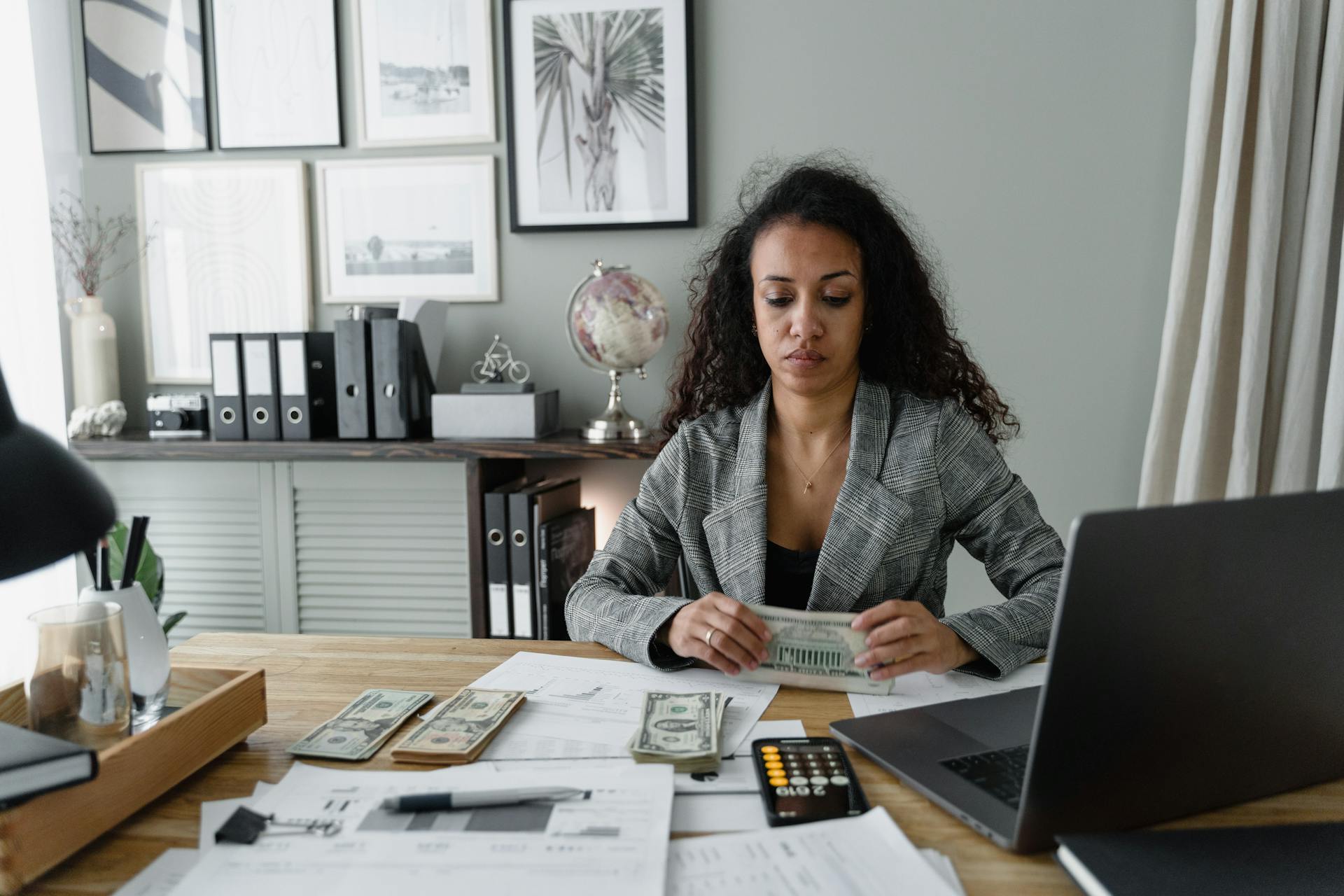 Woman Holding Cash Money Sitting at a Table