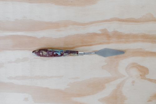 Free Art palette knife with wooden handle placed on a textured wooden surface. Stock Photo