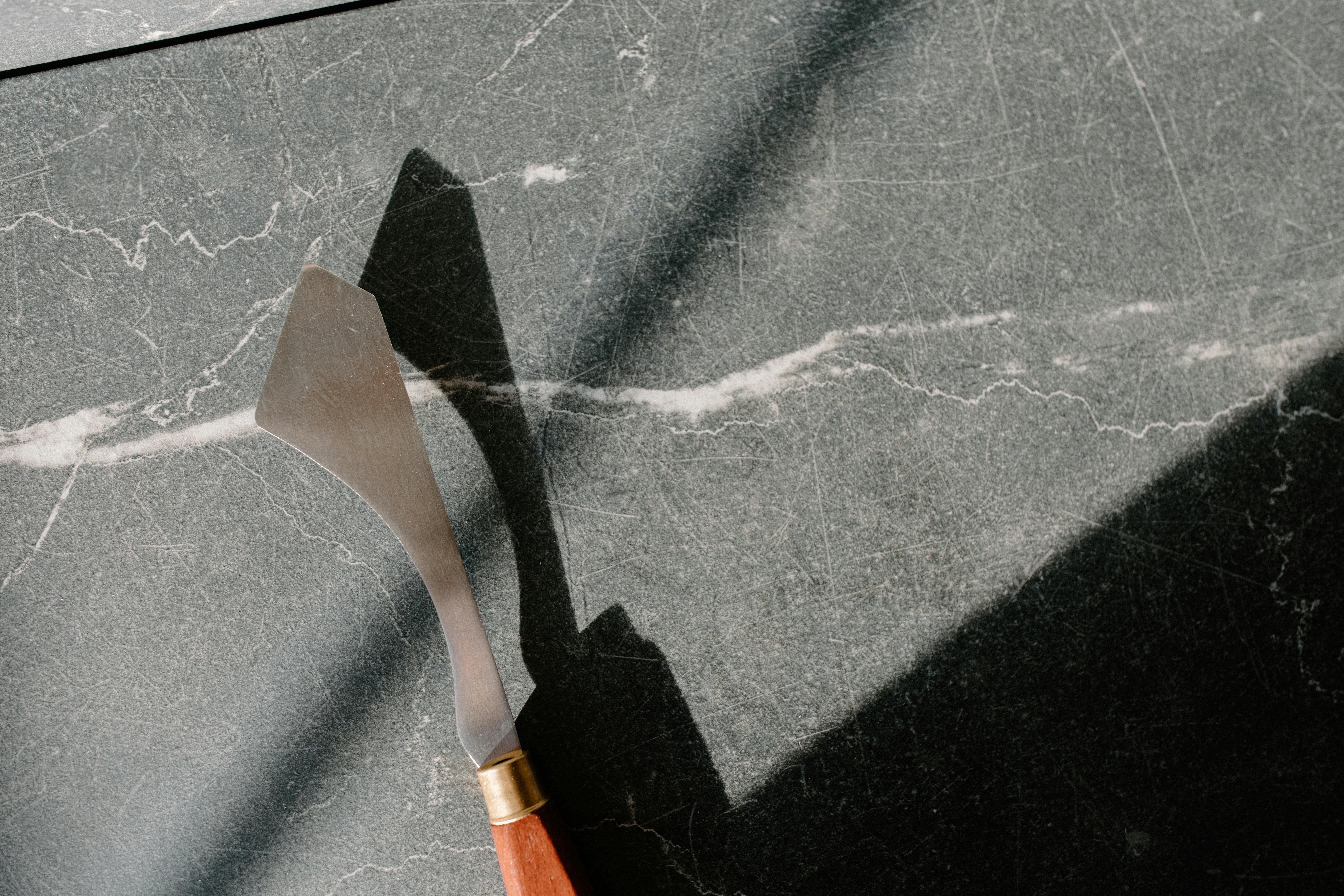 Close-up of a palette knife on marble, showcasing light and shadow play.
