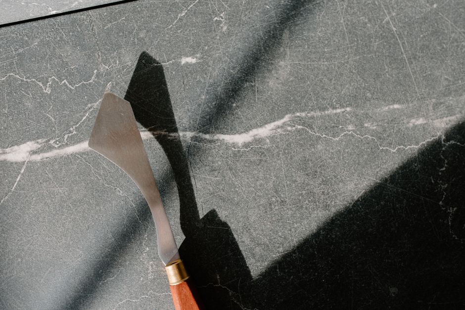 A palette knife is the right tool for lifting wet paint