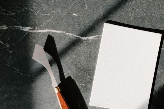 Palette knife and blank canvas on marble background, perfect for artistic projects.