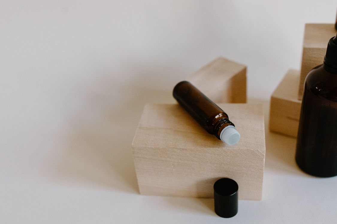 Free Brown Roller Bottle on Wooden Block Stock Photo