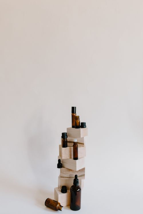 Free Minimalist product photo featuring essential oil bottles on stacked wooden blocks against a neutral background. Stock Photo