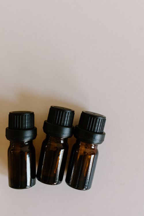 Free Close-up of three amber bottles with black caps used for essential oils on a neutral surface. Stock Photo