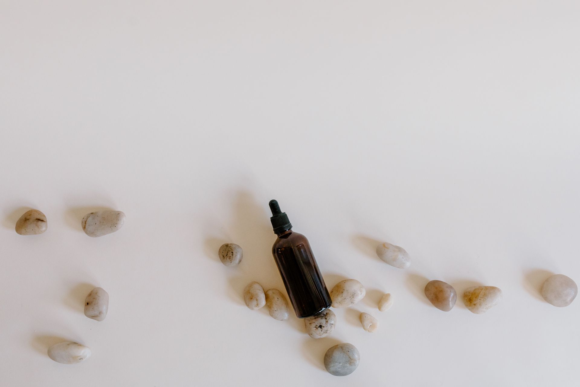 Essential Oil with Stones on White Surface