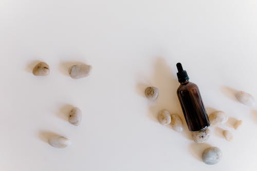 Free Essential Oil with Stones on White Surface Stock Photo