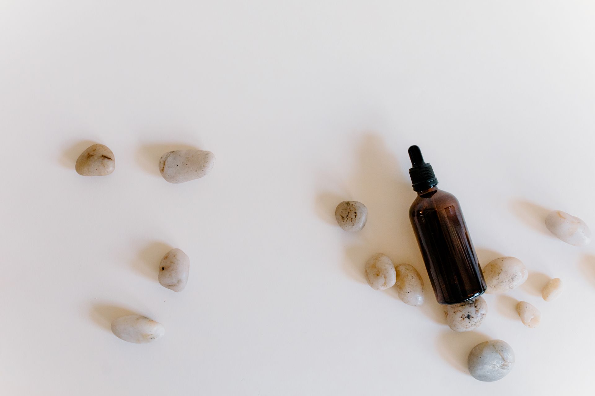 Essential Oil with Stones on White Surface