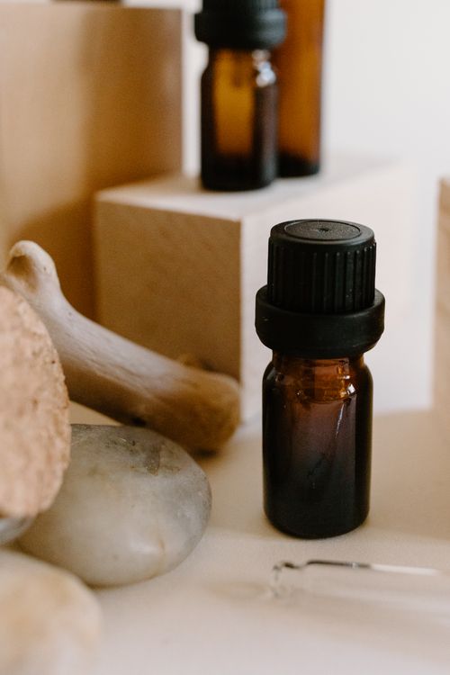 Free Essential oil bottle surrounded by natural stones and wooden blocks, perfect for aromatherapy concepts. Stock Photo