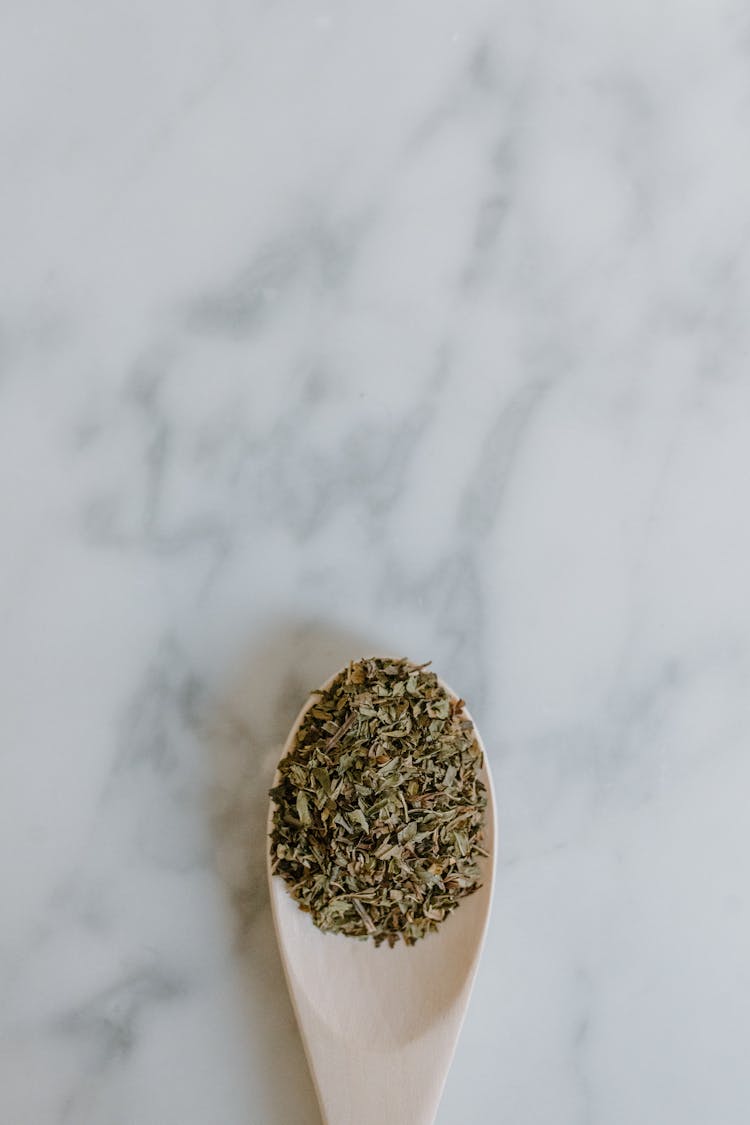 Dried Green Tea Leaves In Spoon On Table