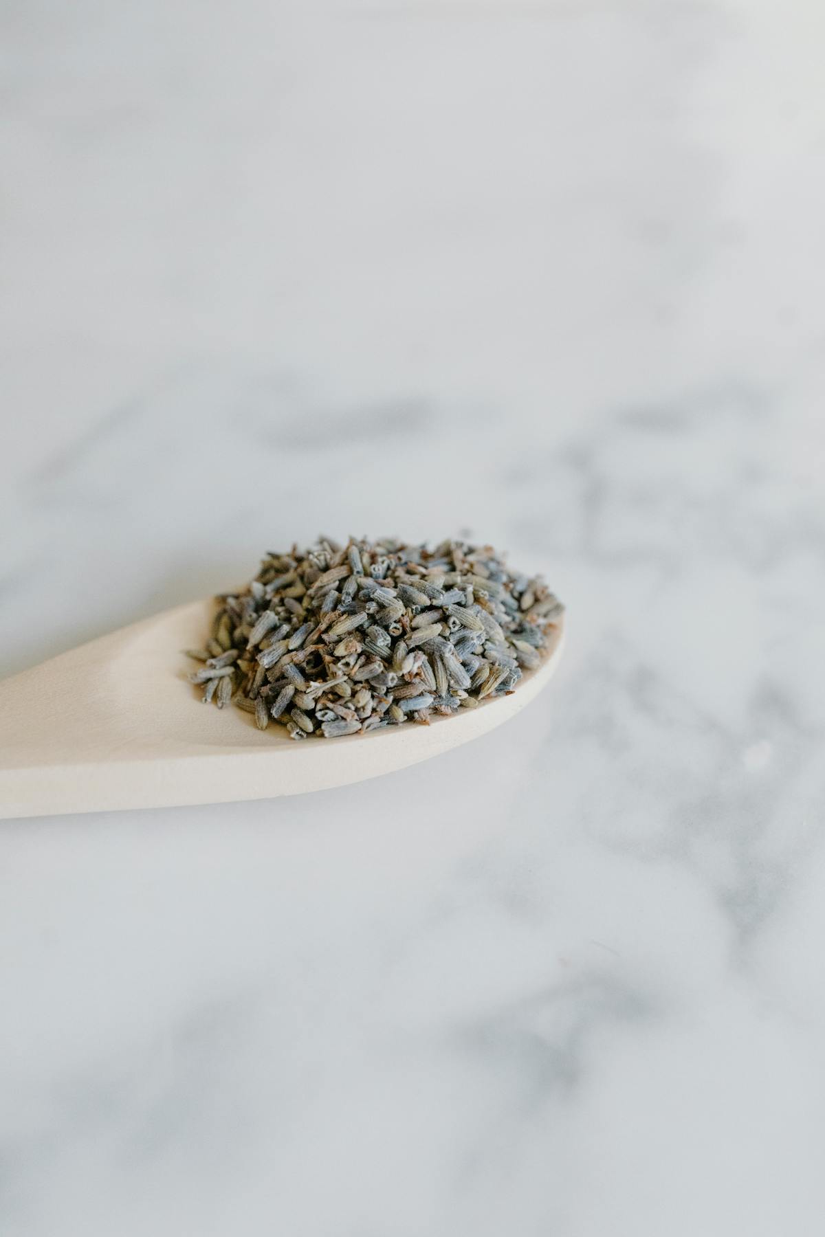 Primo piano di erbe secche su cucchiaio di legno pronte a sbriciolarsi