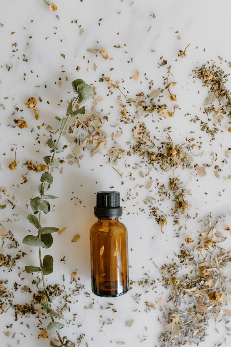 Essential Oil Bottle And Herbal Medicine On White Surface