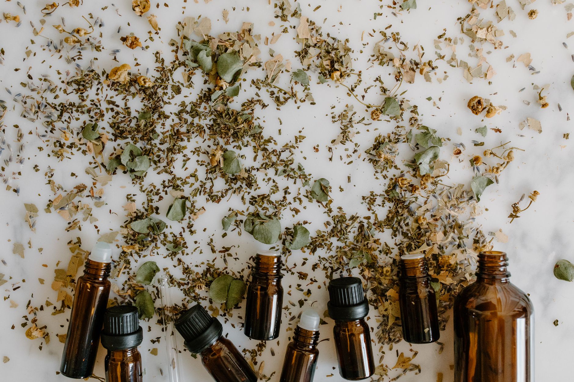 Huiles essentielles avec plantes médicinales naturelles sur surface blanche
