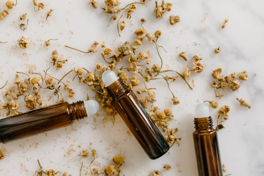 Brown roll-on bottles with dried chamomile flowers on a white background.