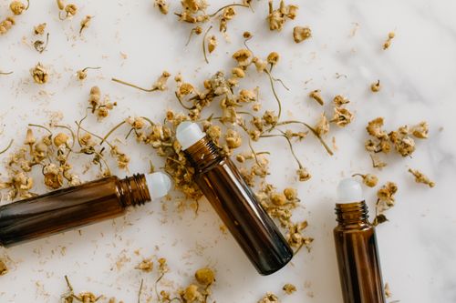 Free Brown roll-on bottles with dried chamomile flowers on a white background. Stock Photo