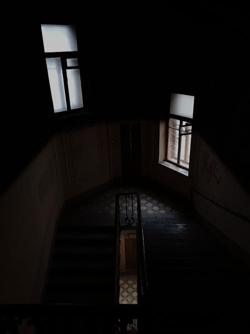 Free From above of staircase with railings inside of residential multistory apartment building with windows and tiled floor with dim light Stock Photo