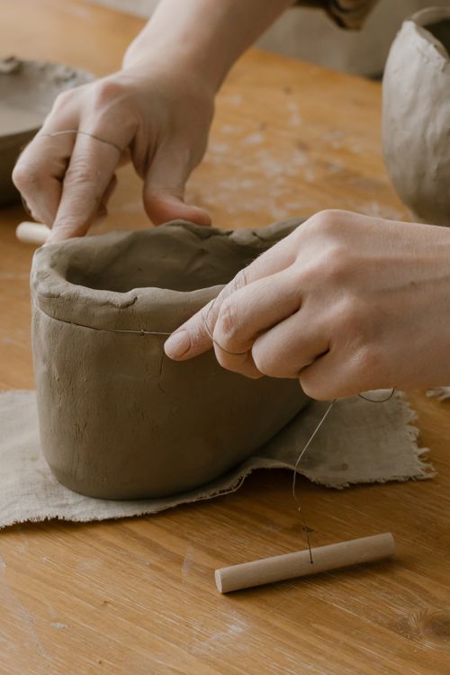 Hands shaping a clay piece in a pottery workshop.