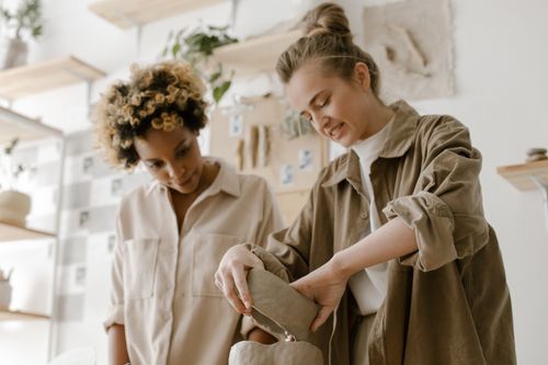 Free Two women engaged in crafting pottery in an artistic and relaxed workshop setting. Stock Photo