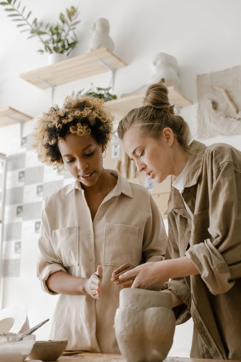 Two makers shaping clay together at a studio worktable