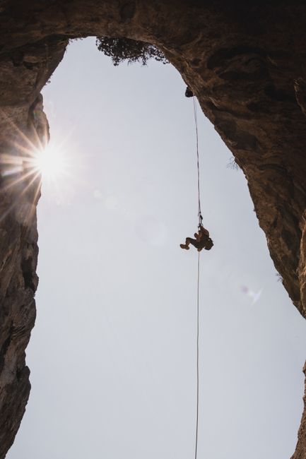 Silhouette of an adventurous climber rappelling down a cliff in Sardinia, Italy.