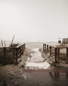 Moody pathway leading to a quiet Sardinian beach under a cloudy sky.