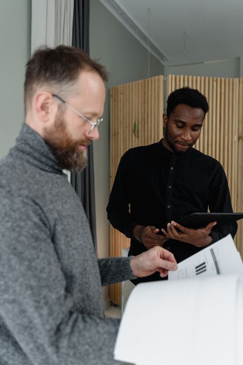 Free Two business professionals working together, reviewing documents in an office setting. Stock Photo