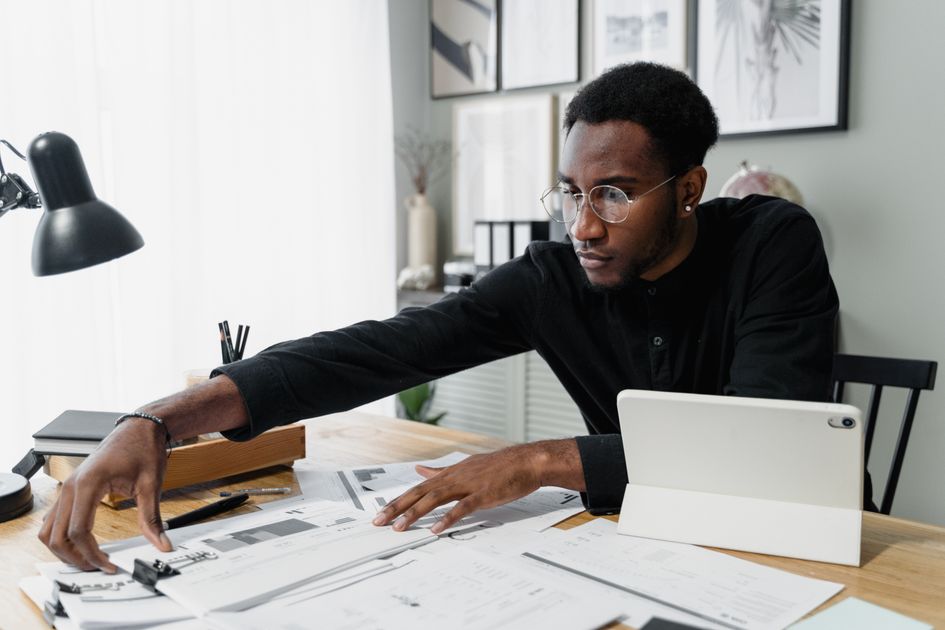 Un professionnel à son bureau examine des documents financiers à côté d'une tablette.