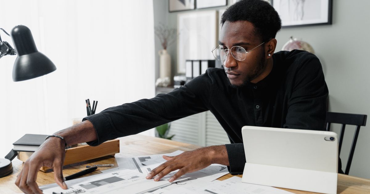 Un professionnel à son bureau examine des documents financiers à côté d'une tablette.