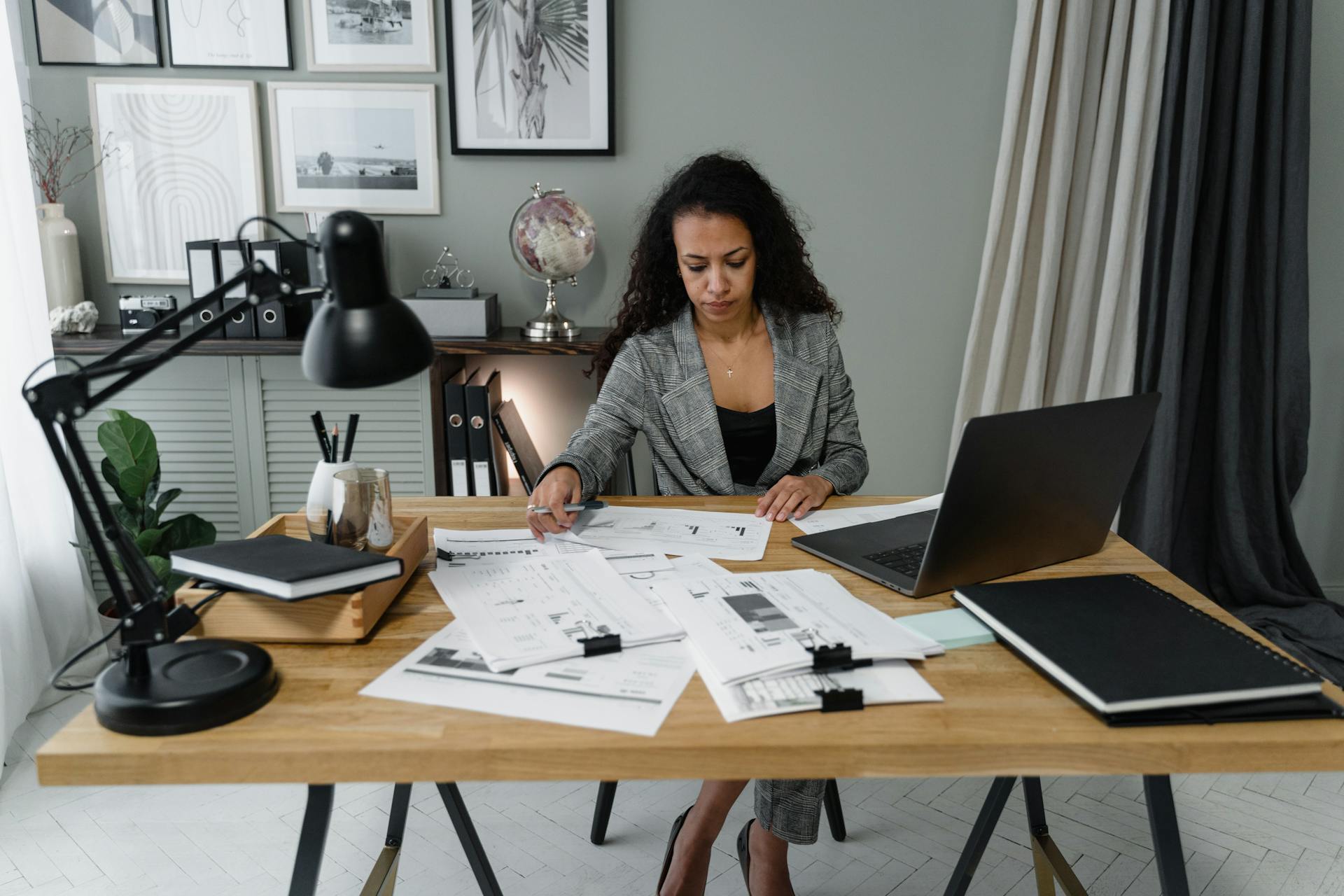 A focused businesswoman reviewing documents in a modern office setting, emphasizing professional determination.