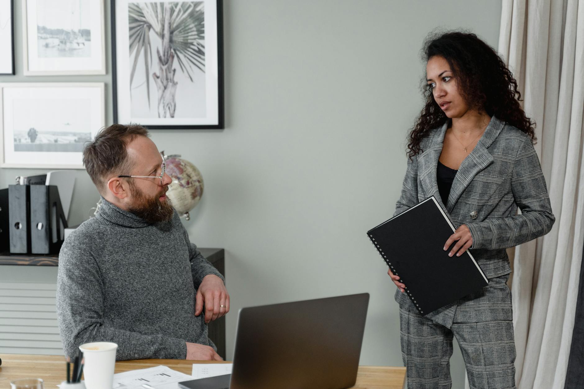 A man and woman discuss work in a stylish office environment with modern decor.