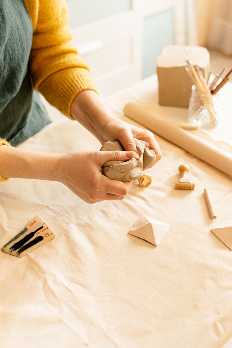 A Person Breaking A Clay Dough