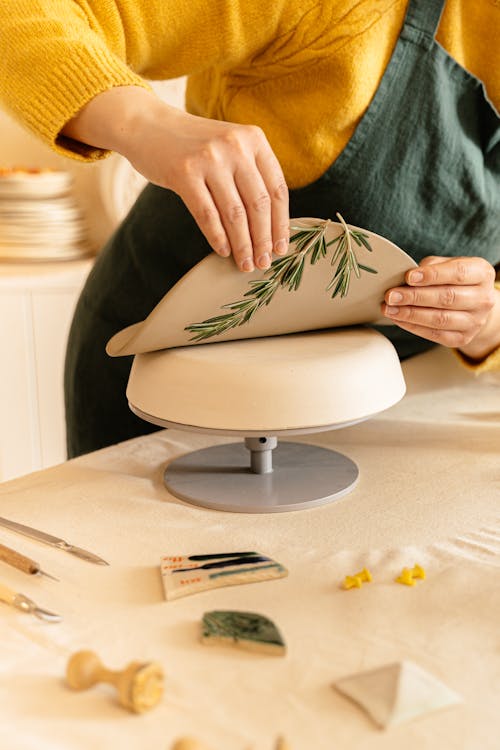 A Person Pressing Rosemary on flatten Clay
