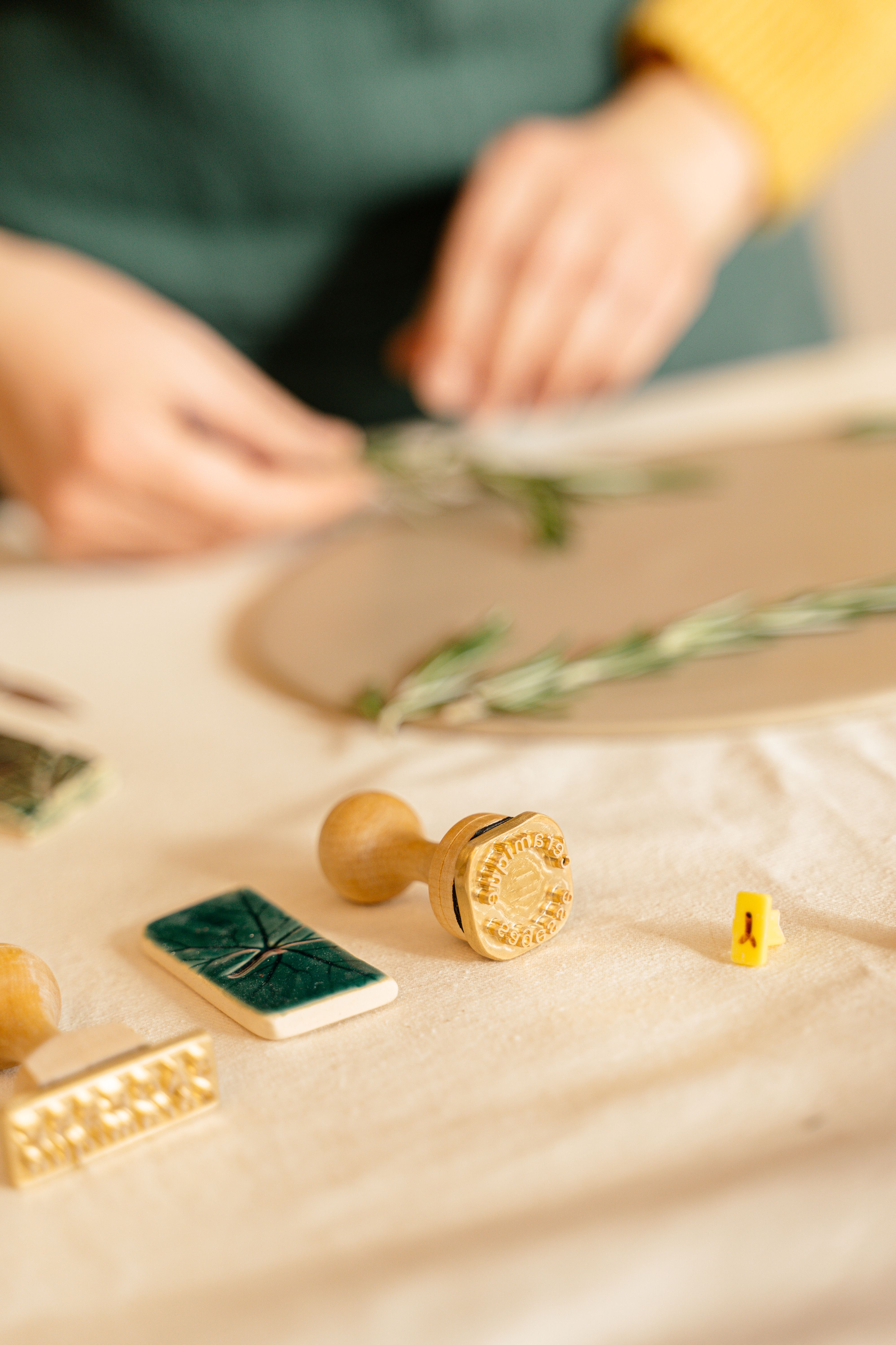 Close-up of hands creating art with wooden stamps and crafting tools on a table.