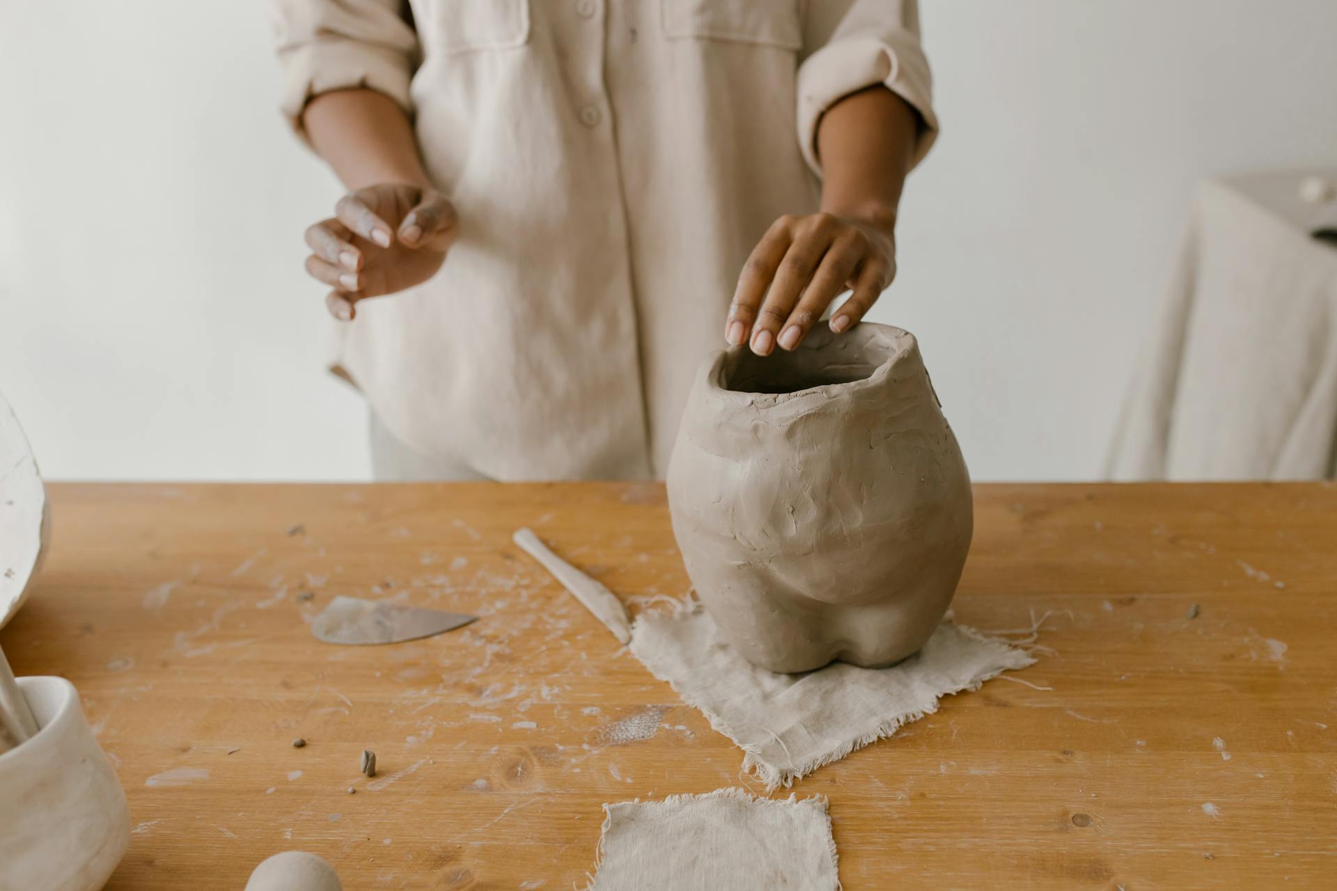 Hands crafting pottery in a ceramic studio. Artistic process of creating handmade clay sculptures.