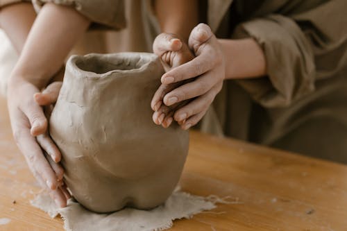 People Molding a Clay Pot on a Wooden Table