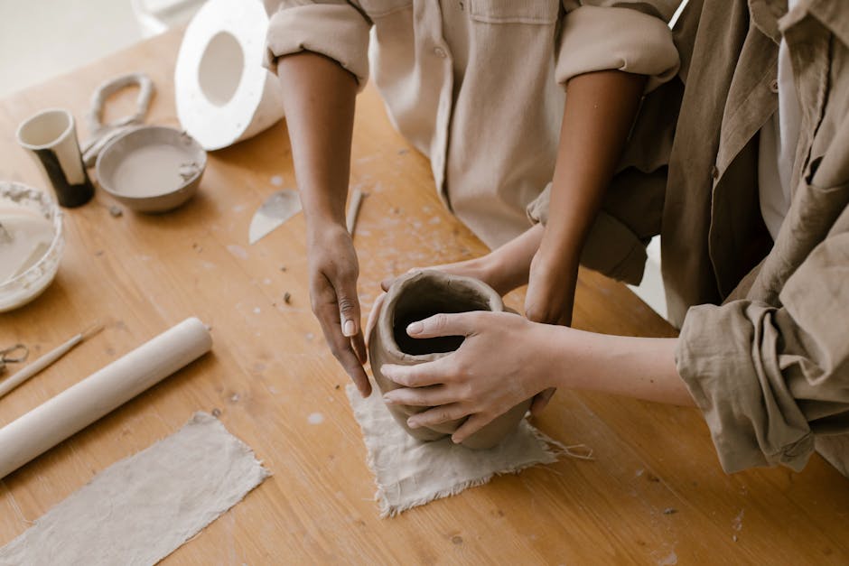Close-up of hands crafting a pottery vase in an art studio setting.