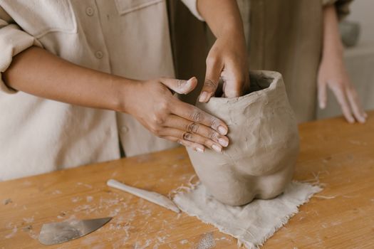 Artisan crafting a clay pot with hands in a pottery workshop. Creative pottery making process.