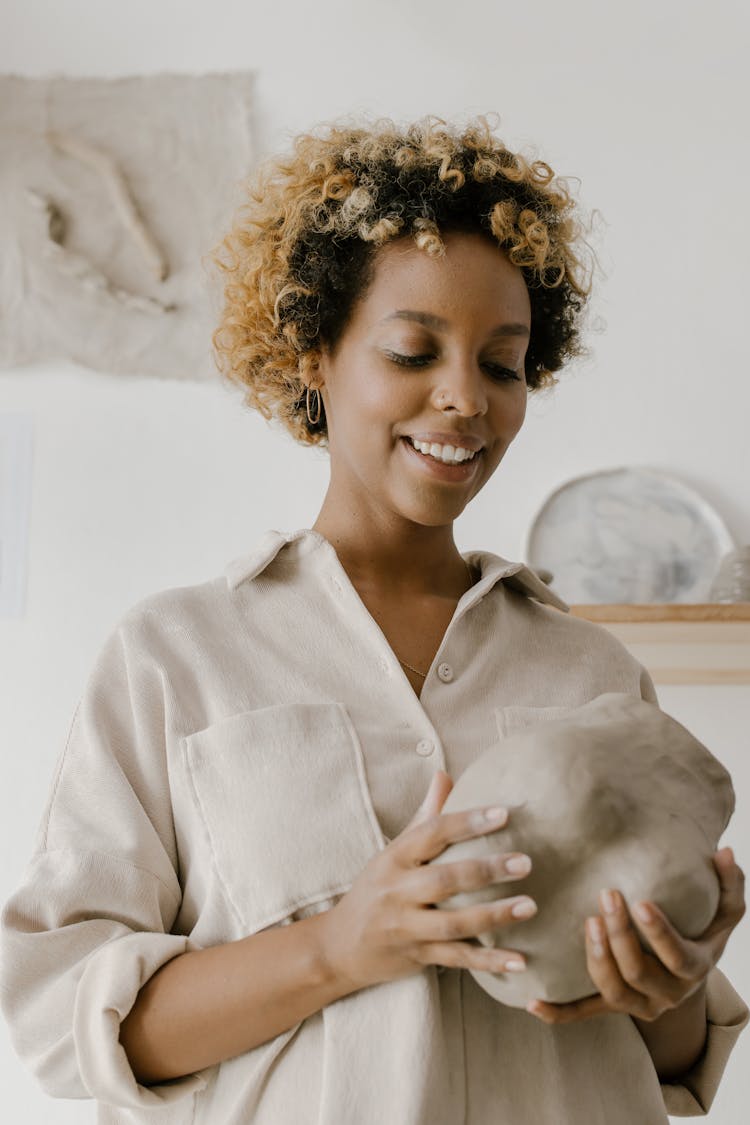 A Woman In Beige Top Holding A Stone Object